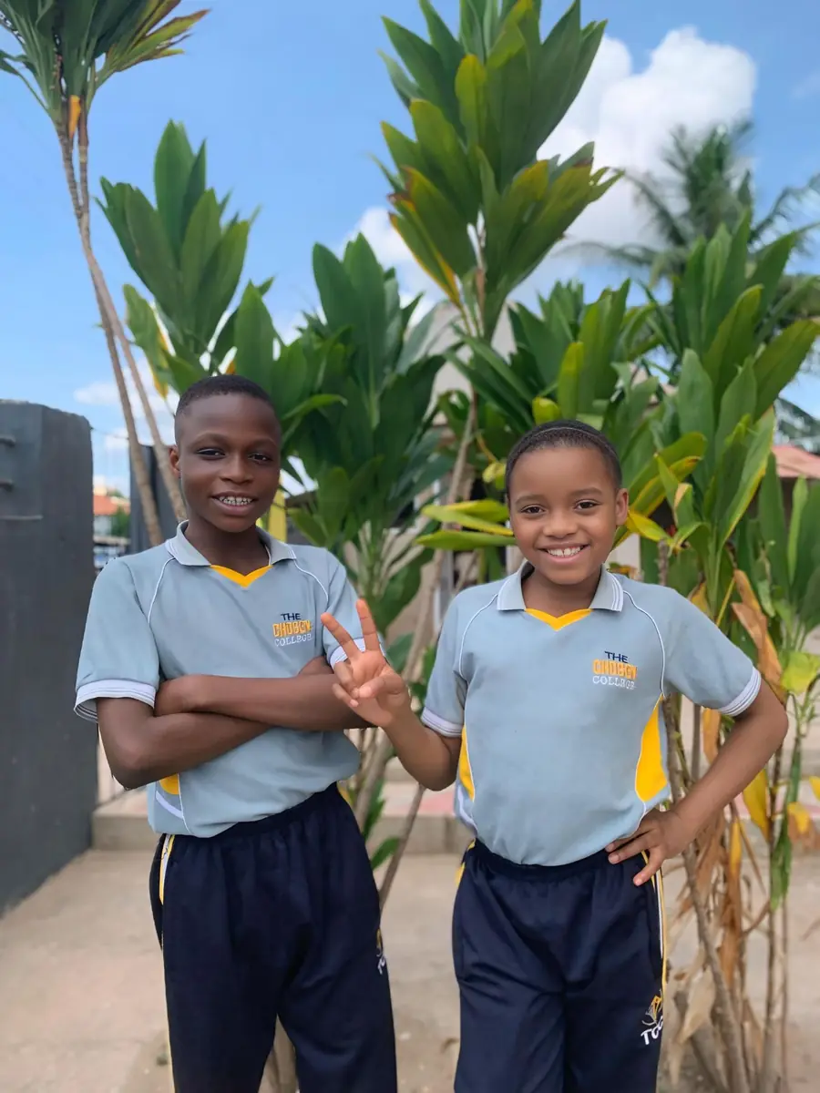 Two students of The Chosen College in blue shirts among tropical plants