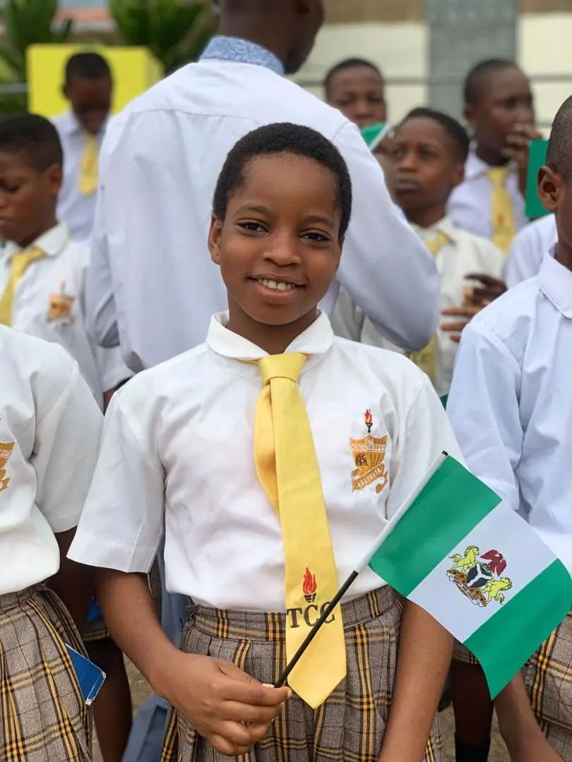 A smiling student of The Chosen College holding a Nigerian flag