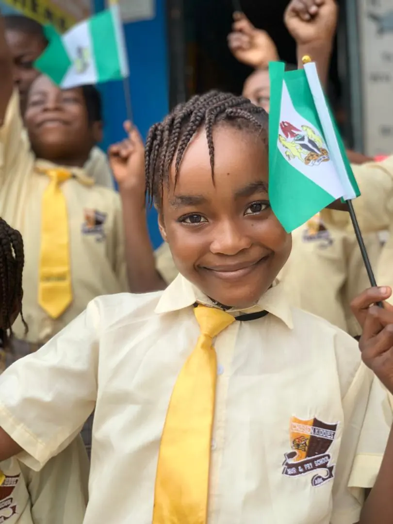 A smiling Chosen Kiddies pupil holding a Nigerian flag