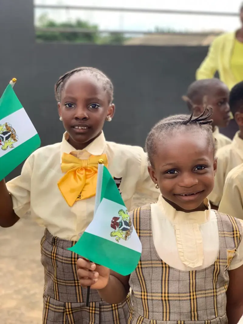 Two Chosen Kiddies pupils holding Nigerian flags