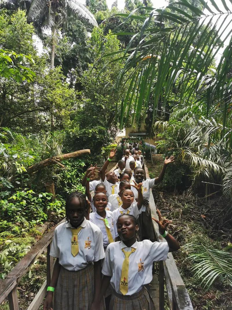 Students waving as they walk along a forest boardwalk