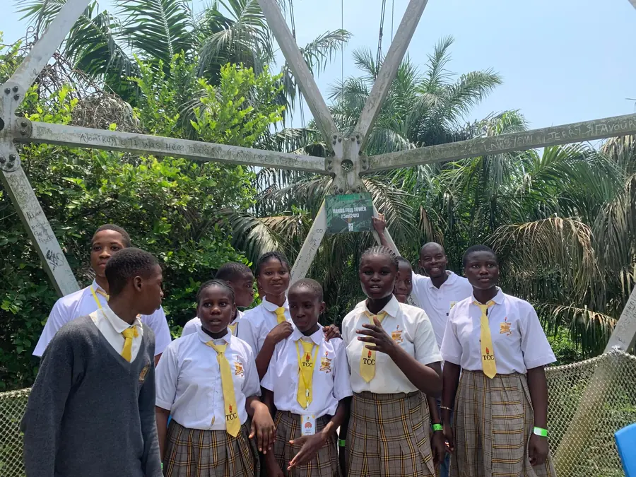 Students and a teacher gathered beneath a canopy walkway tower